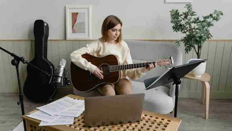 Woman practicing guitar indoors with music sheets and microphone. Ideal for music hobby themes., tags: muziek - pexel